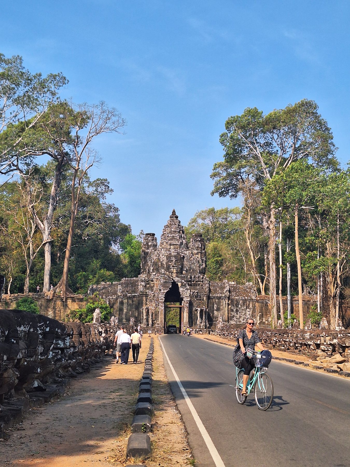 The road running through a stone gate at Angkor Thom with a cyclist, Cambodia