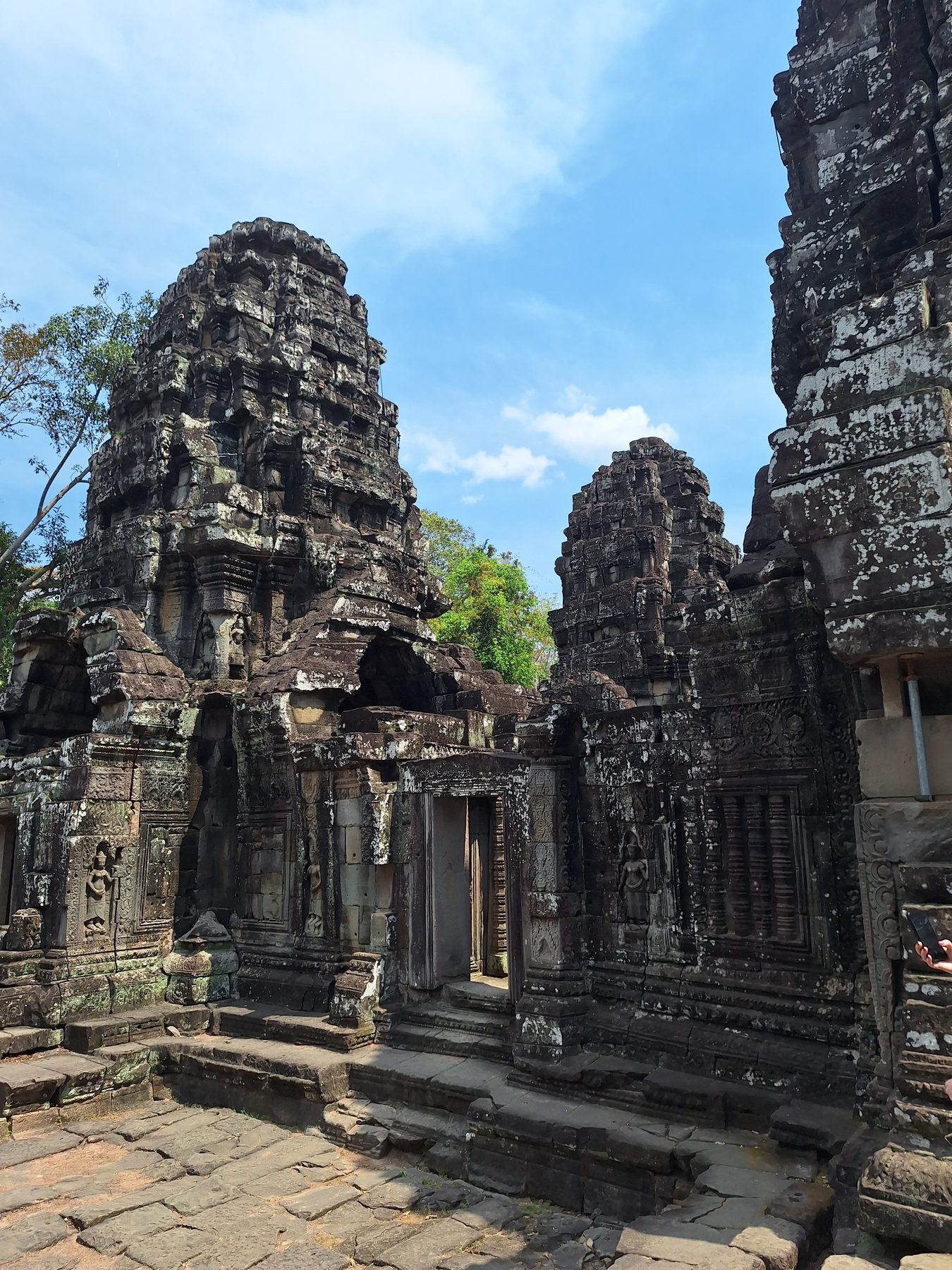 Weathered stone towers of an Angkor temple against a blue sky, Cambodia