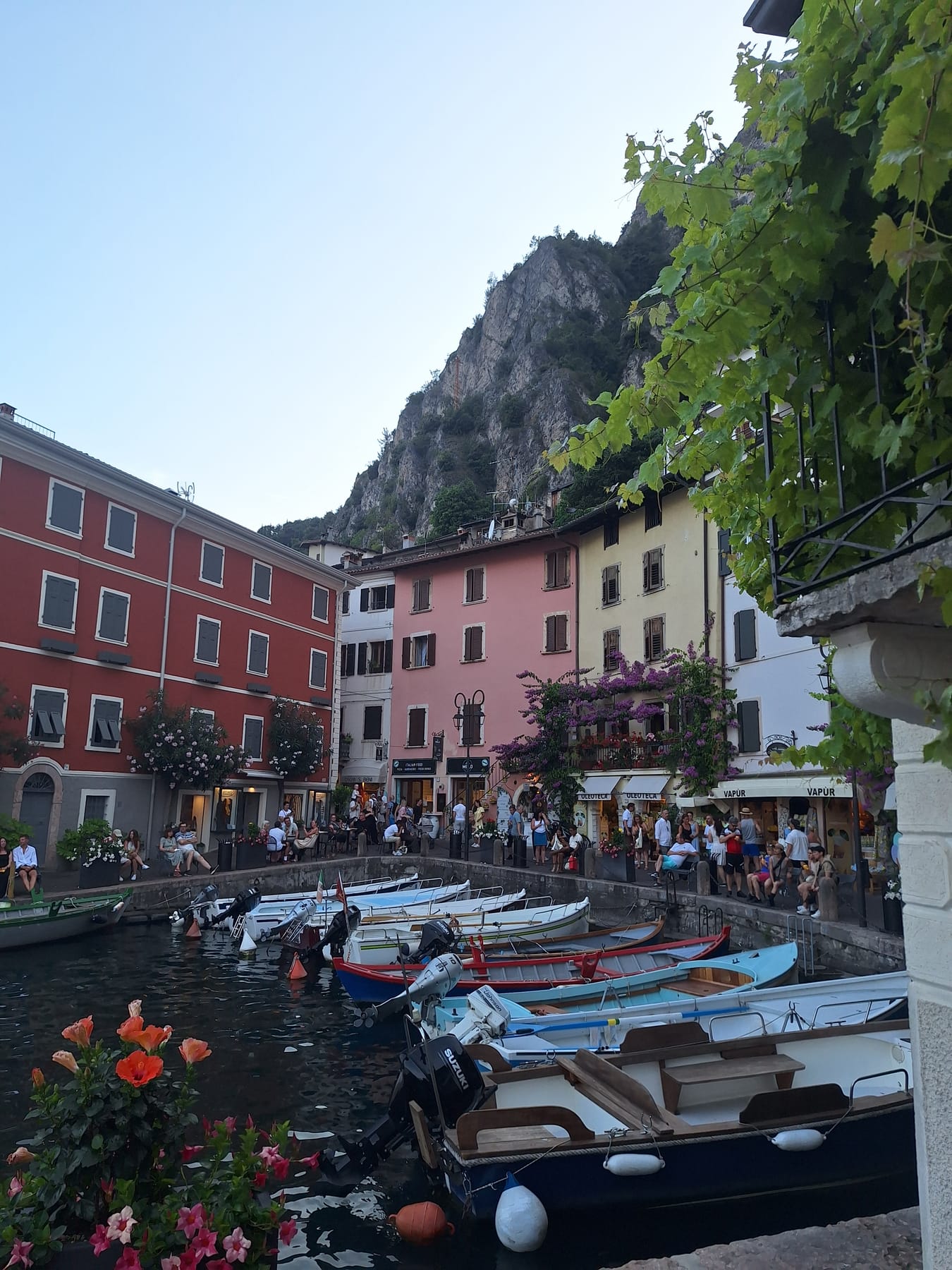 Painted houses around Limone's small harbour, with wooden boats in the water and a cliff rising behind