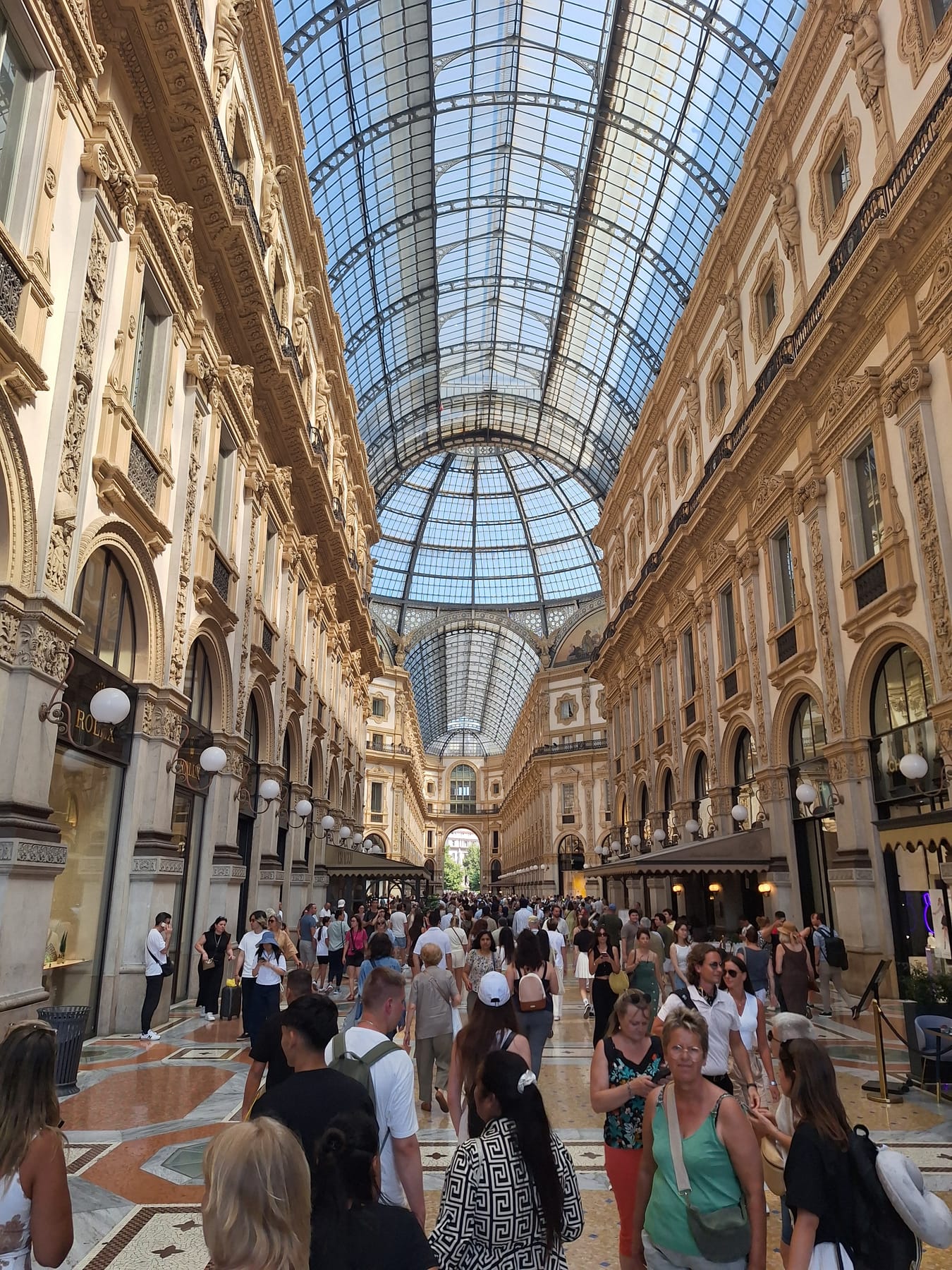 Crowds under the glass and iron roof of the Galleria Vittorio Emanuele II, lined with ornate shopfronts