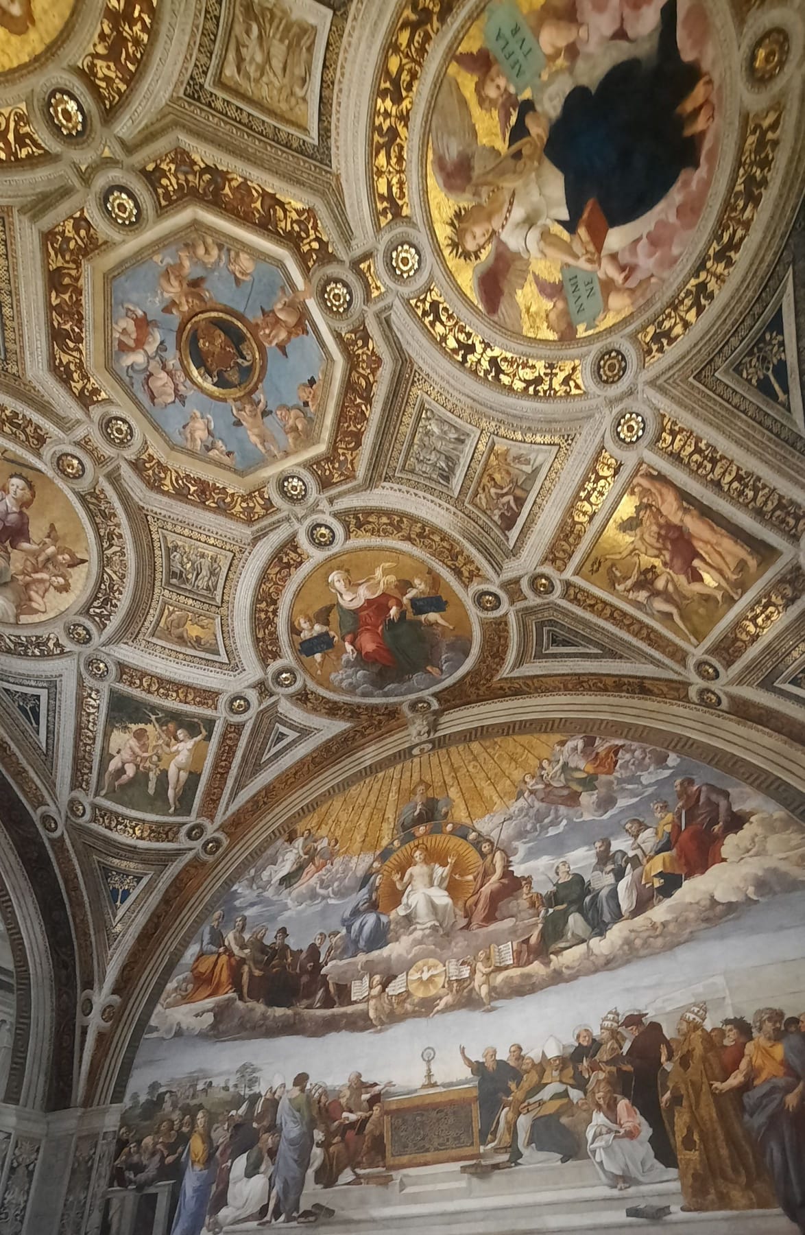 The ornate gilded ceiling of one of the Raphael Rooms in the Vatican, above Raphael's fresco of the Disputation