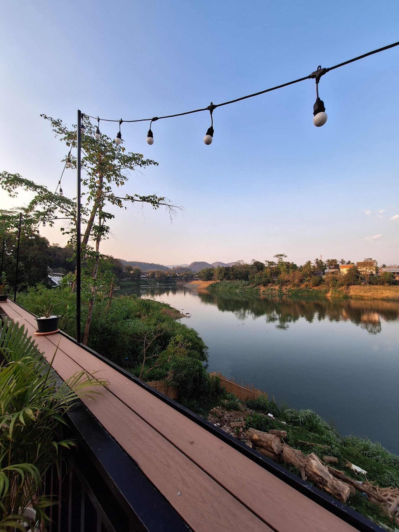 A riverside terrace strung with lights at sunset in Luang Prabang