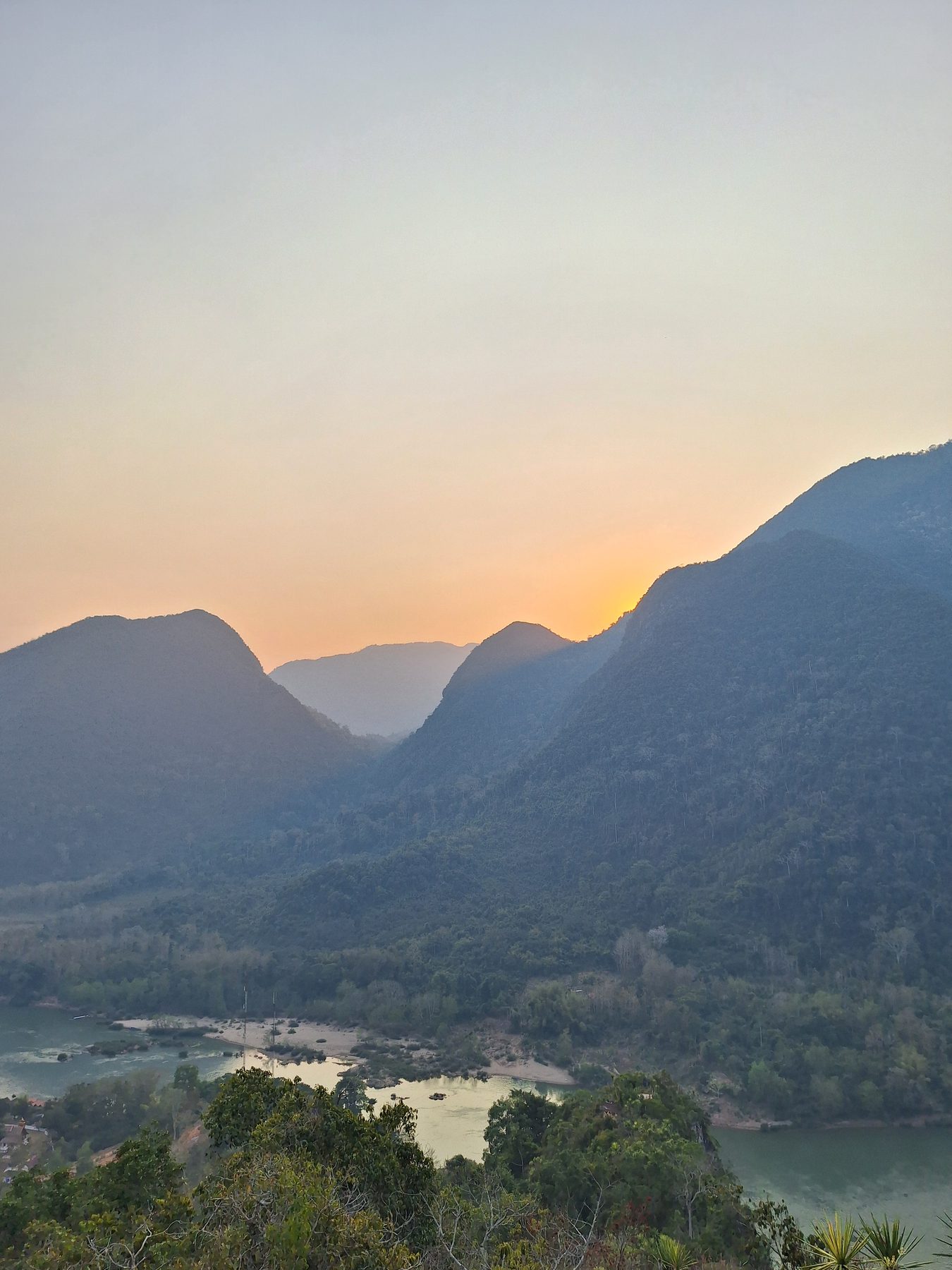 The sun setting between mountain ridges above the Nam Ou river at Muang Ngoi, Laos