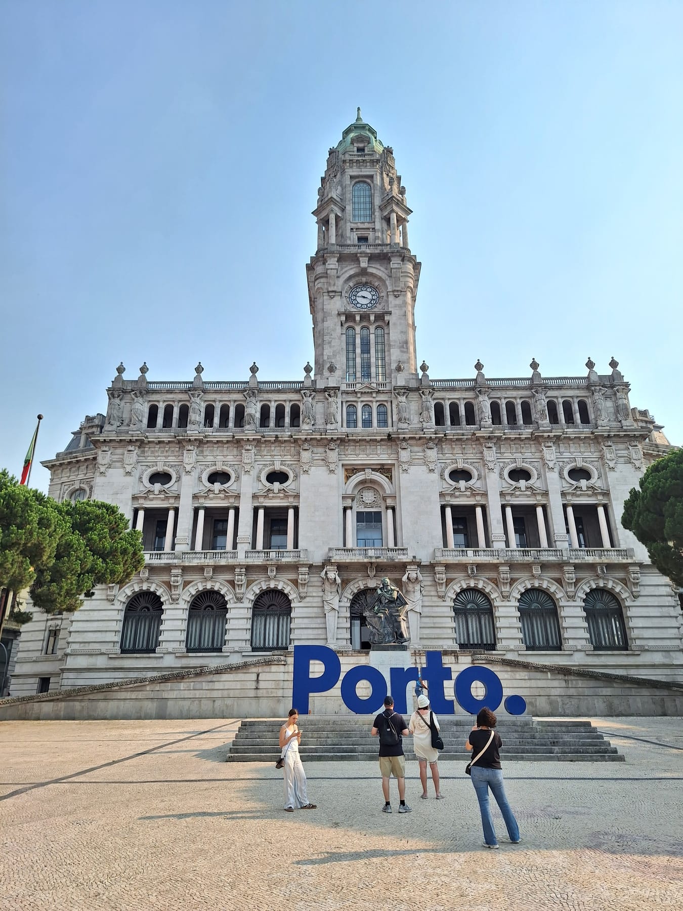 Porto's granite town hall with its clock tower, and large blue letters spelling Porto in front of the steps