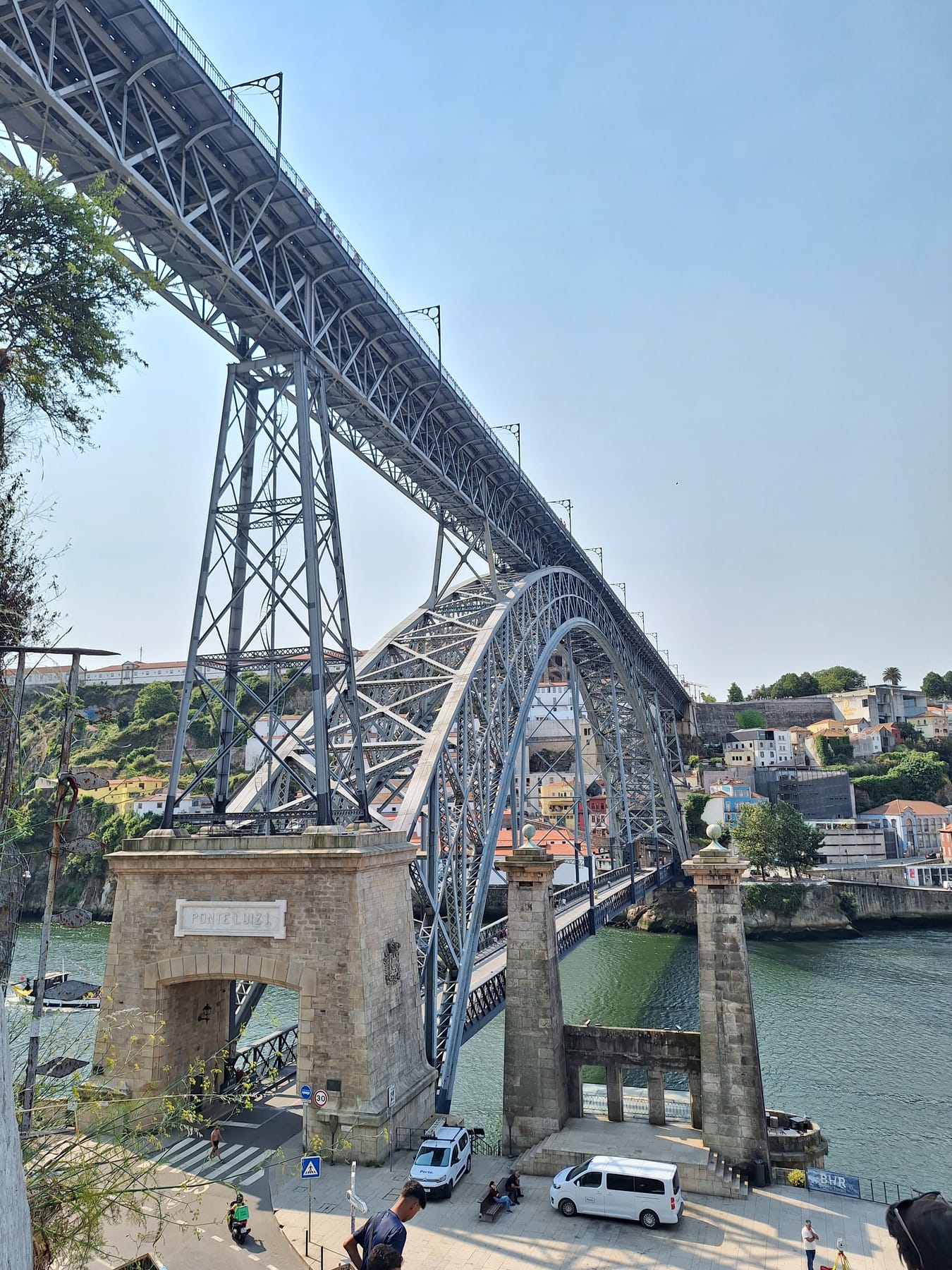 The iron arch of the Dom Luís I bridge spanning the Douro, with its stone pillars at the riverbank