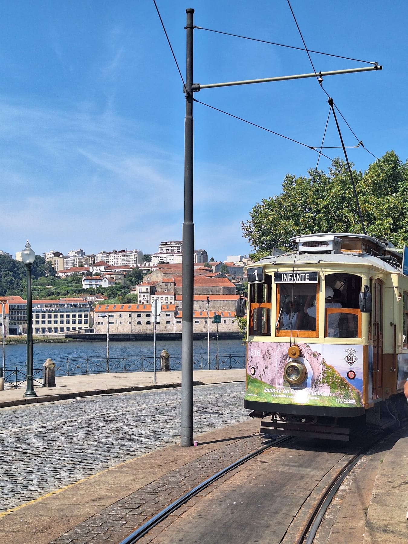 A vintage yellow tram marked Infante on the riverside line in Porto, with Gaia across the water