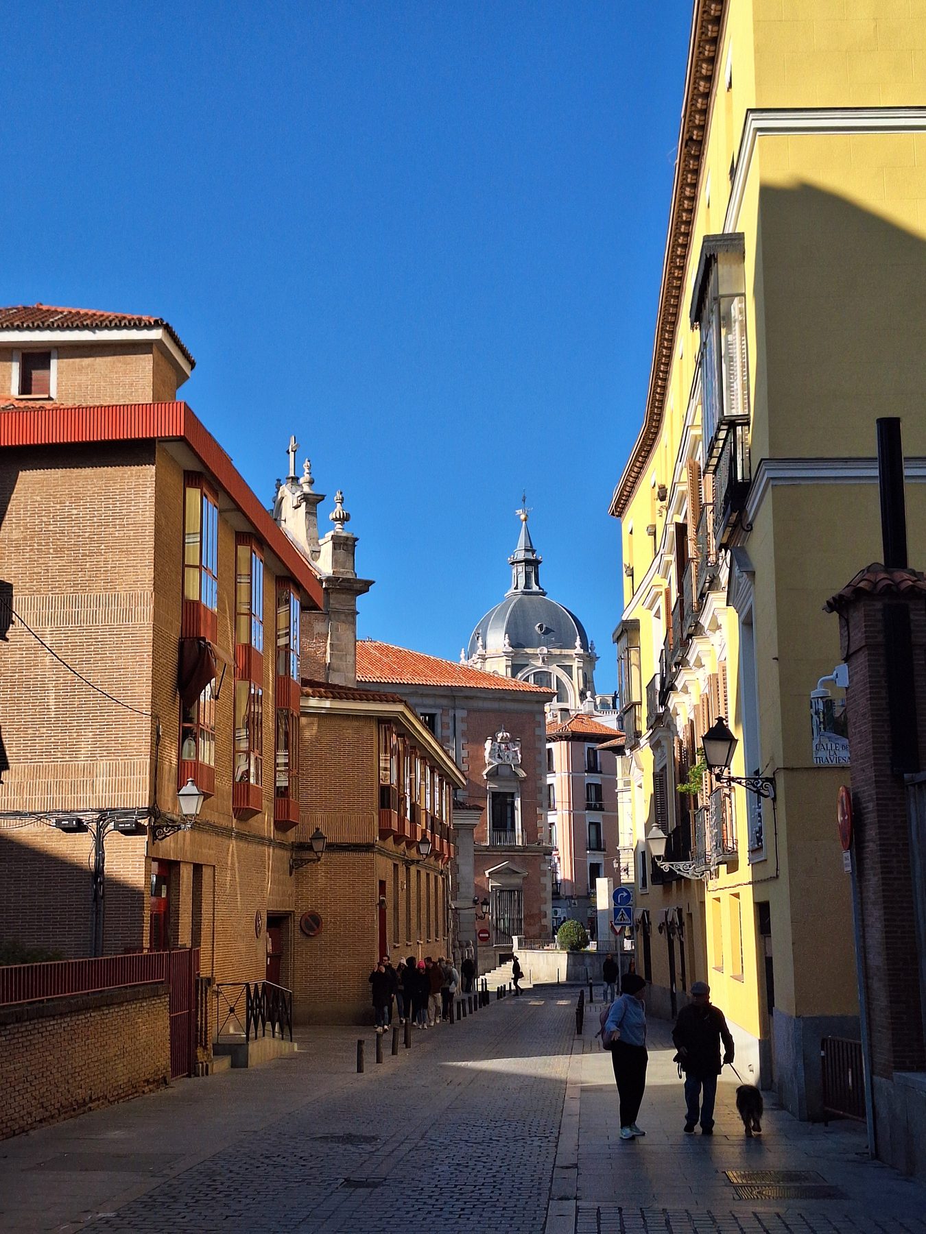 A street of balconied buildings in central Madrid running downhill towards the Almudena cathedral dome