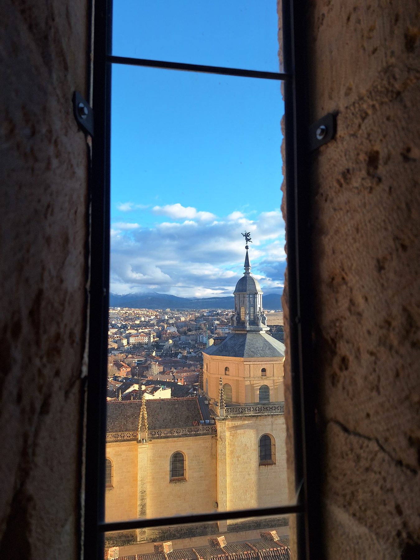 Segovia cathedral seen through an open window in a thick stone wall