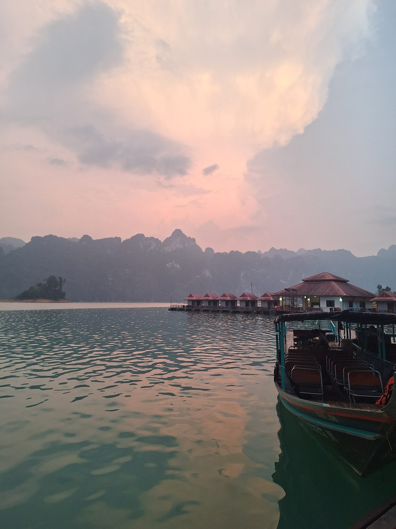 A longtail boat moored at floating bungalows at sunset on Cheow Lan Lake, Thailand