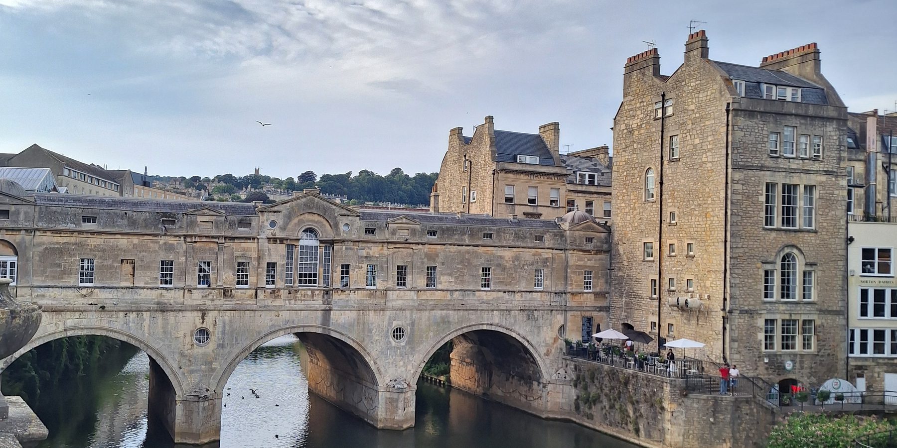 Pulteney Bridge and its weir on the River Avon in Bath, with honey-coloured stone buildings above