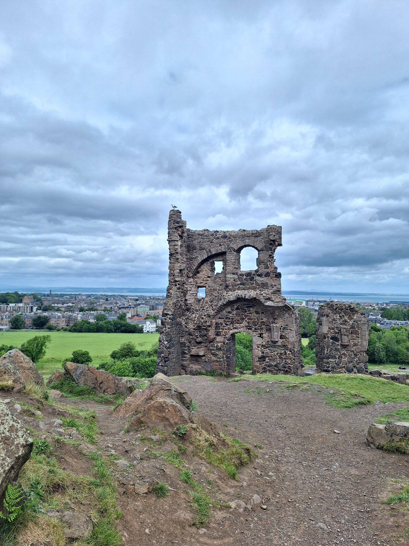 The stone ruin of a small chapel standing on a hillside above Edinburgh