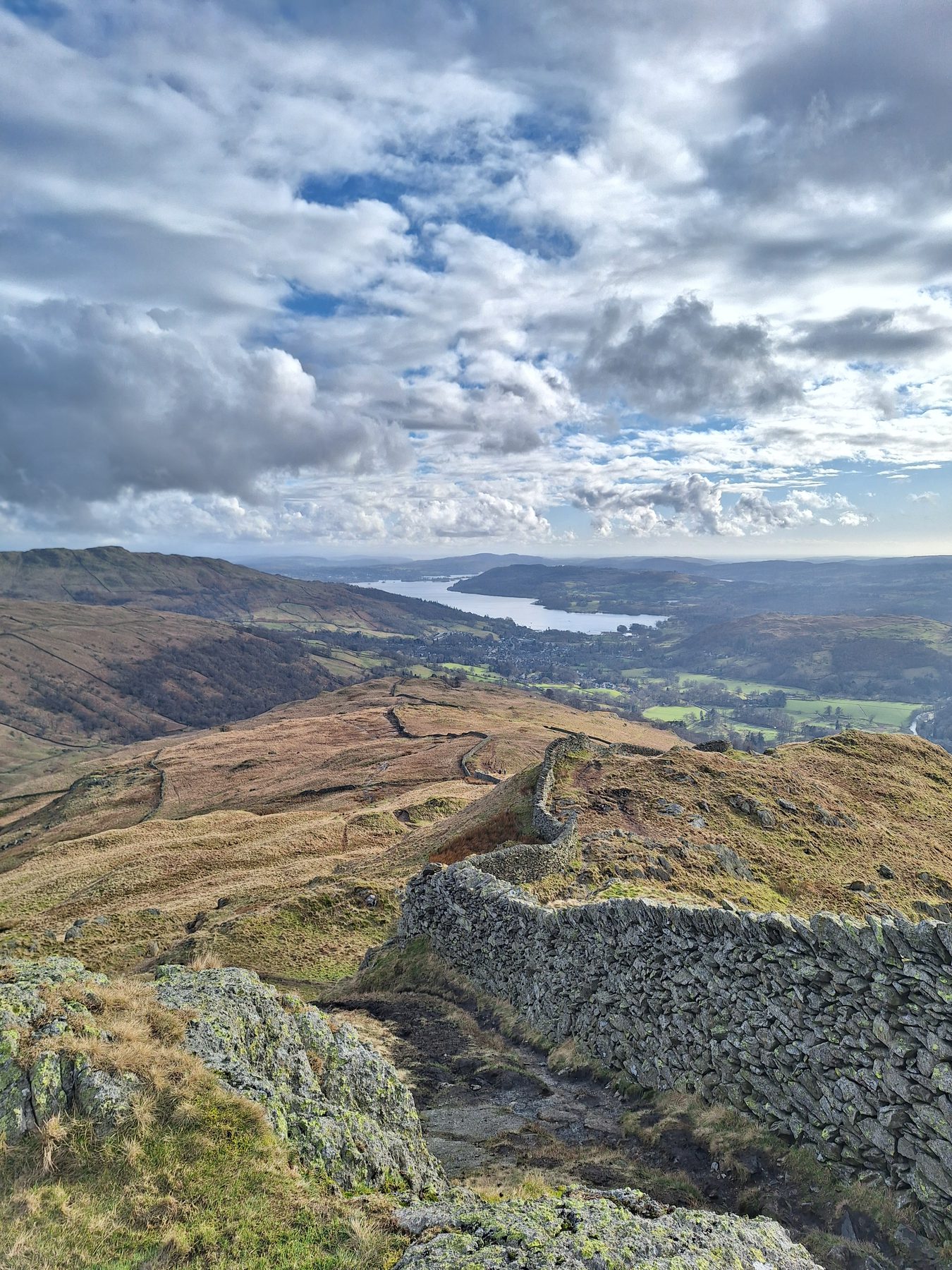 A grassy fell top looking down over Windermere in the Lake District