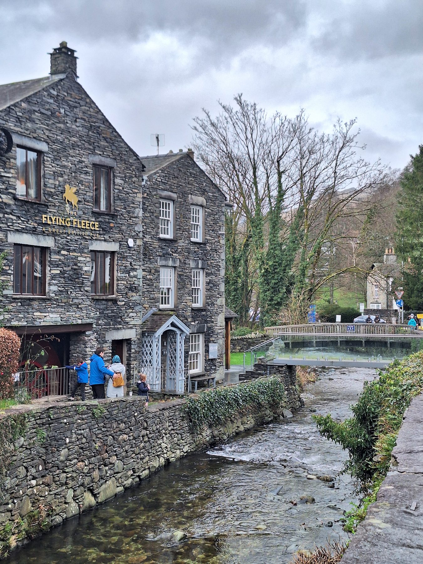 Stone slate-roofed buildings beside a rocky beck running through a Lake District village