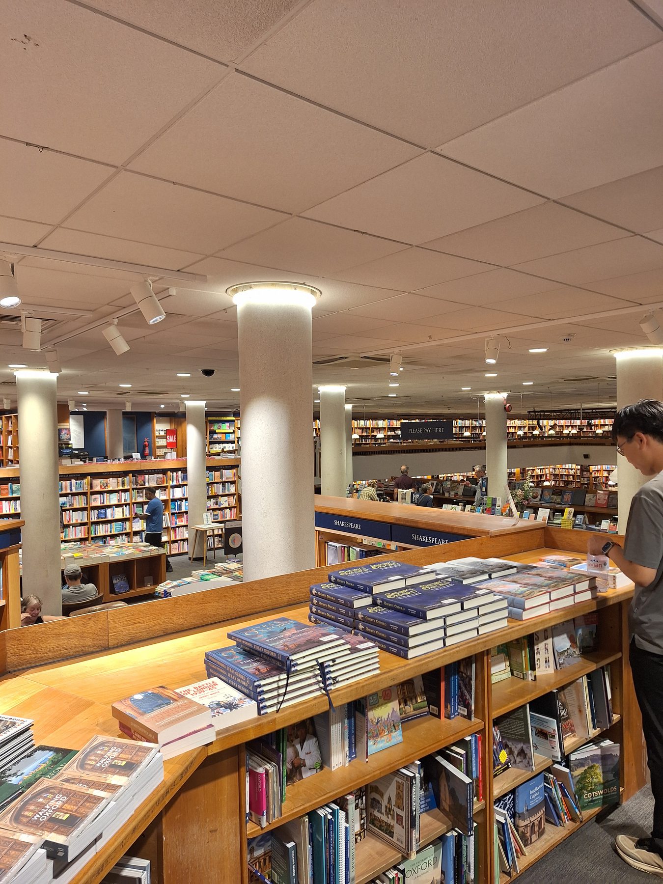 The interior of a large bookshop with long tables of books and shelves stretching away