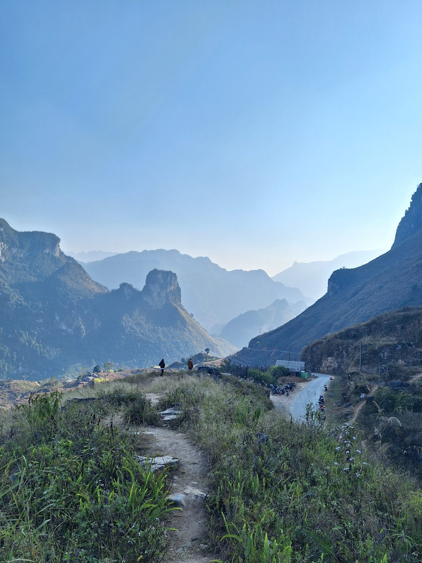 Hazy limestone peaks above a village and a winding road on the Ha Giang Loop, northern Vietnam
