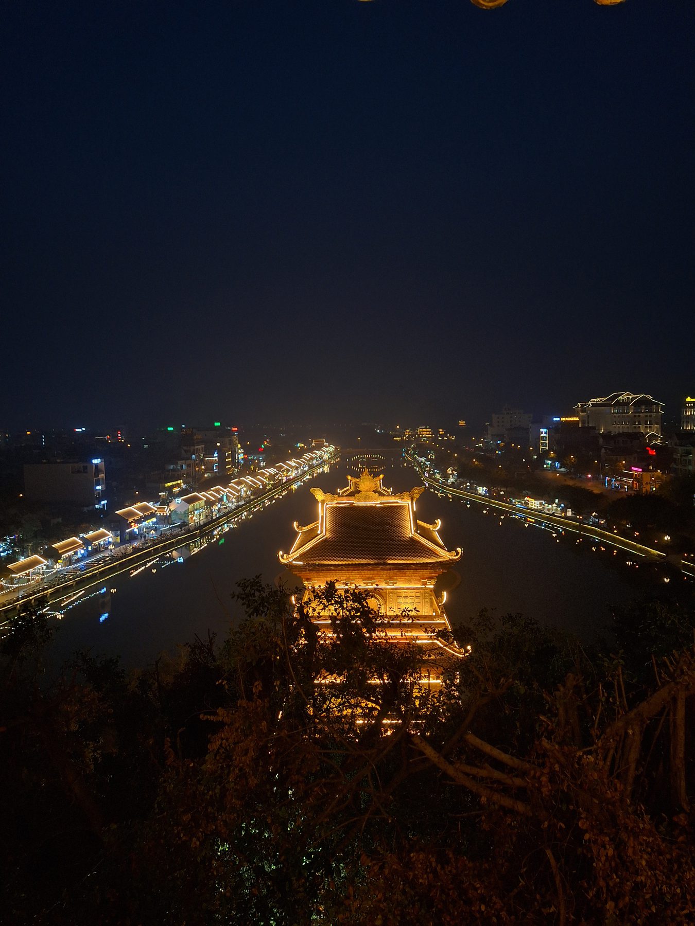 A lit pavilion reflected in water at night in Ninh Binh, Vietnam