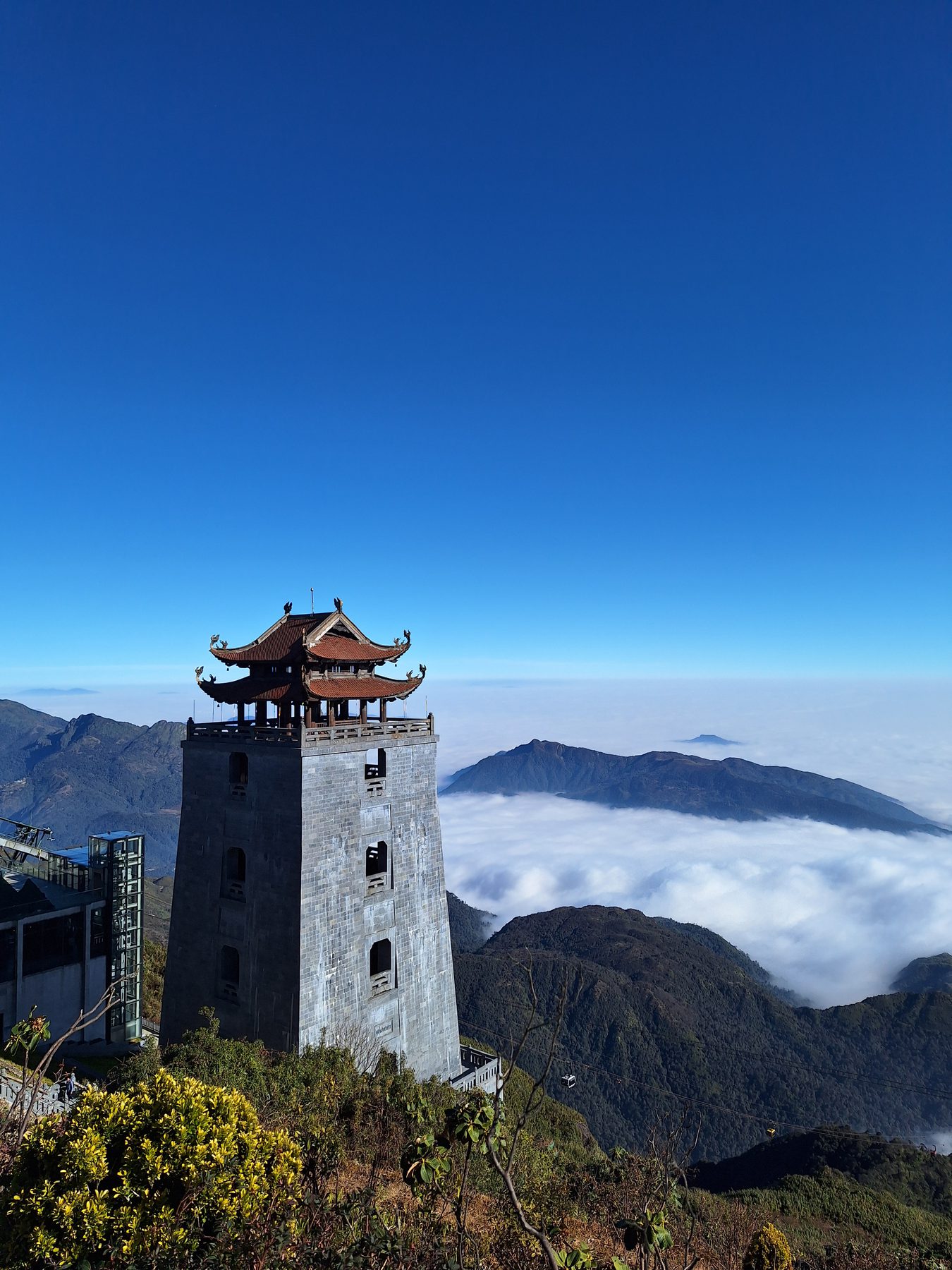 A stone tower on the Fansipan summit ridge standing above a solid layer of cloud, Sapa, Vietnam